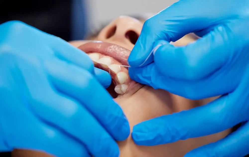 Dentista con guanti blu tratta paziente.