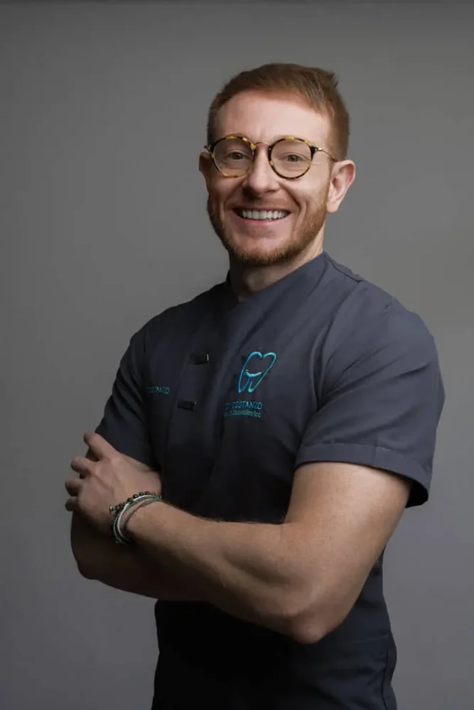 Dentista sorridente in camice grigio.